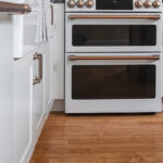 Shows the double oven with the bold gold handles, and the natural wood floors