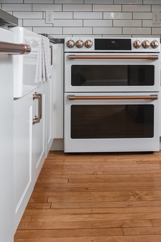 Shows the double oven with the bold gold handles, and the natural wood floors