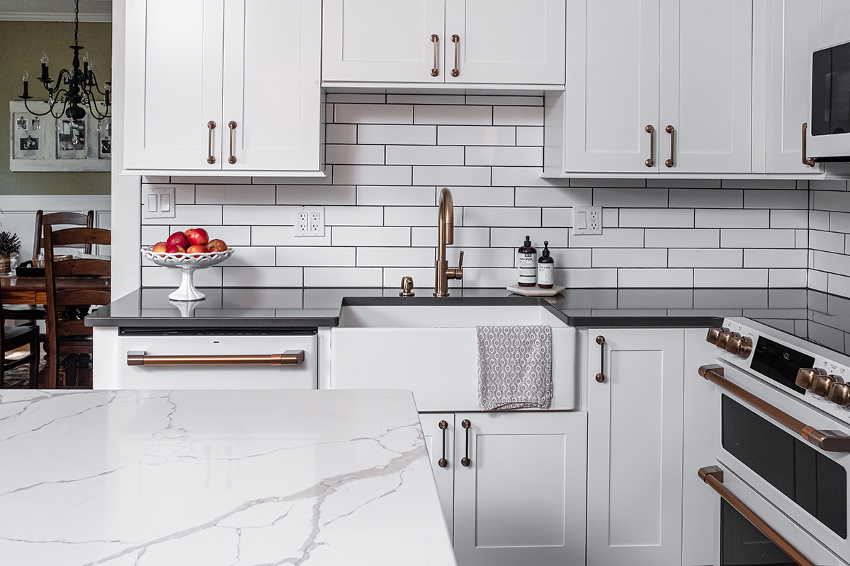 Shows the white farmhouse sink with white tile background.