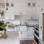 Shows white marble island in contrast to the black countertops along the wall.