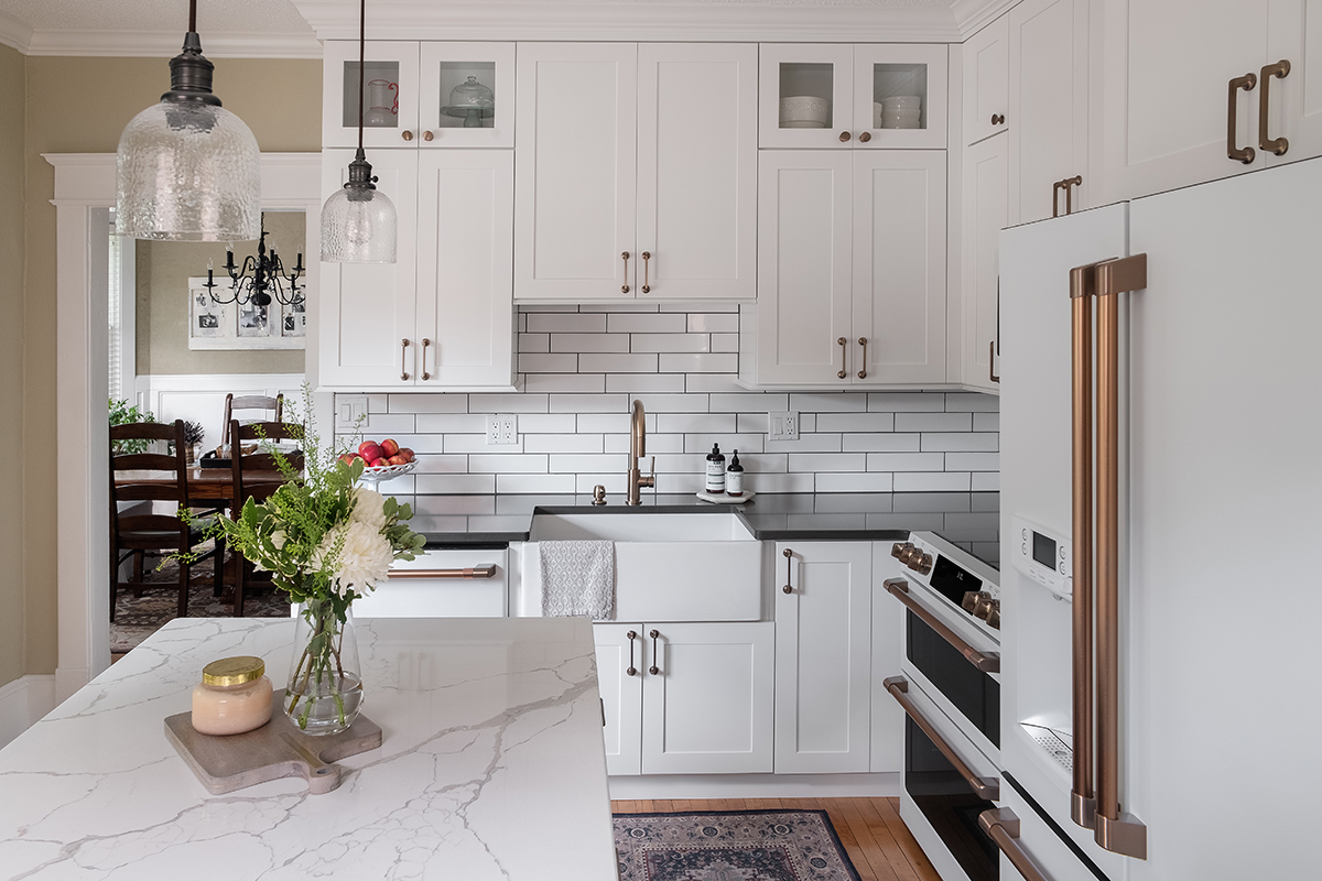 Shows white marble island in contrast to the black countertops along the wall.