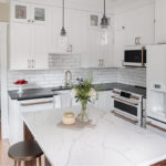 Shows the kitchen from another angle with the white marble counter top in contrast to the black counter along the wall