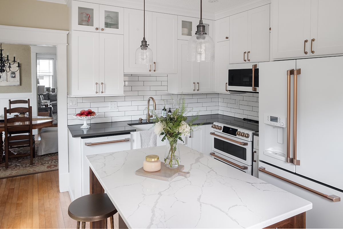 Shows the kitchen from another angle with the white marble counter top in contrast to the black counter along the wall
