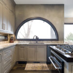 Shows kitchen sink with beige cabinets.