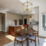 open kitchen with white countertop island. White cabinets line the kitchen surrounding stainless steel appliances.