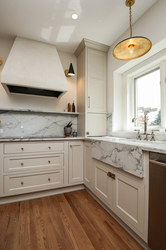 white kitchen cabinetry with silver accents throughout. Marbled white stone countertops and sink.