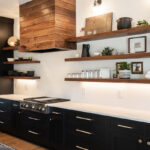 Black cabinets on the lower half of the kitchen with walnut shelves. White counters are shown with a featured a walnut hood.