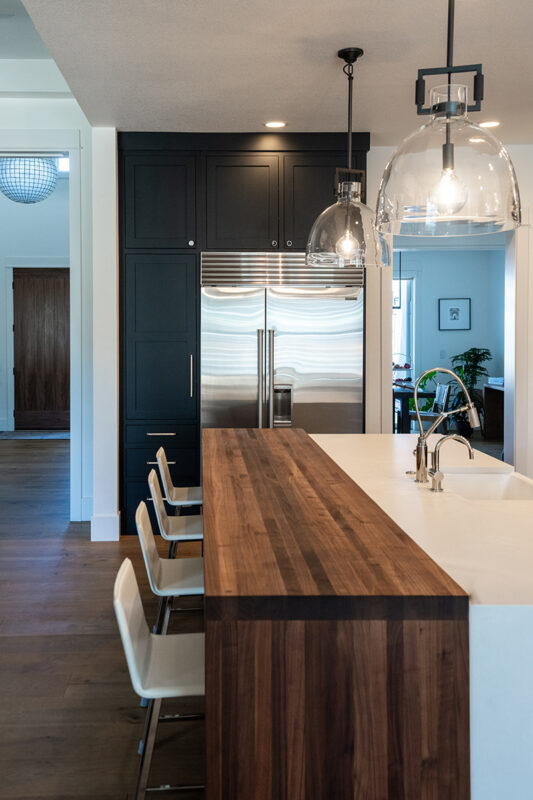 Another view of the walnut bar top that is attached to the island with the white bar stools