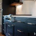 Shows the black cabinets with silver handles and the built in lights under the walnut shelving.