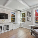 Shows the corner of the built-in cabinets. With the corner windows and the overstuffed chairs.