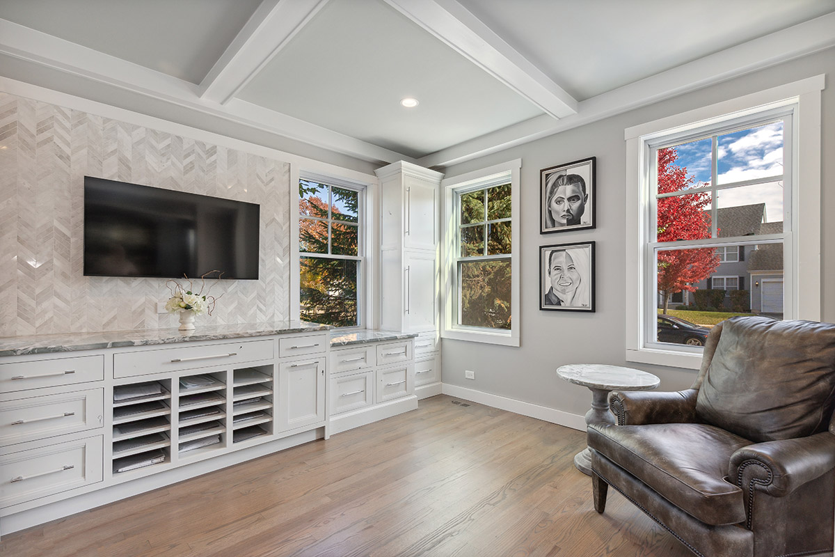 Shows the corner of the built-in cabinets. With the corner windows and the overstuffed chairs.