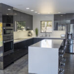 End view of the small kitchen with the dark cabinets and white island.