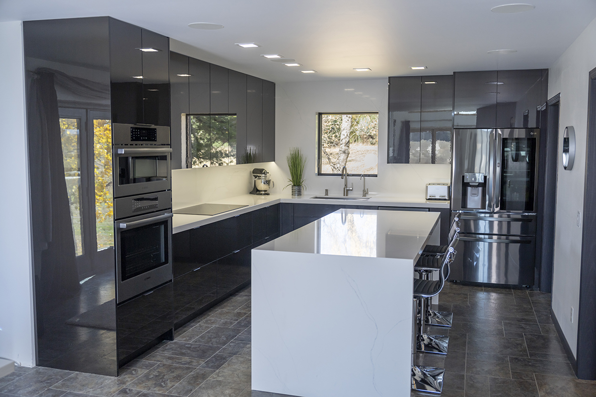 End view of the small kitchen with the dark cabinets and white island.