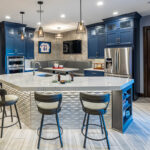 Shows a basement bar with blue cabinets. The bar top has a wavy grey feature under the countertop.