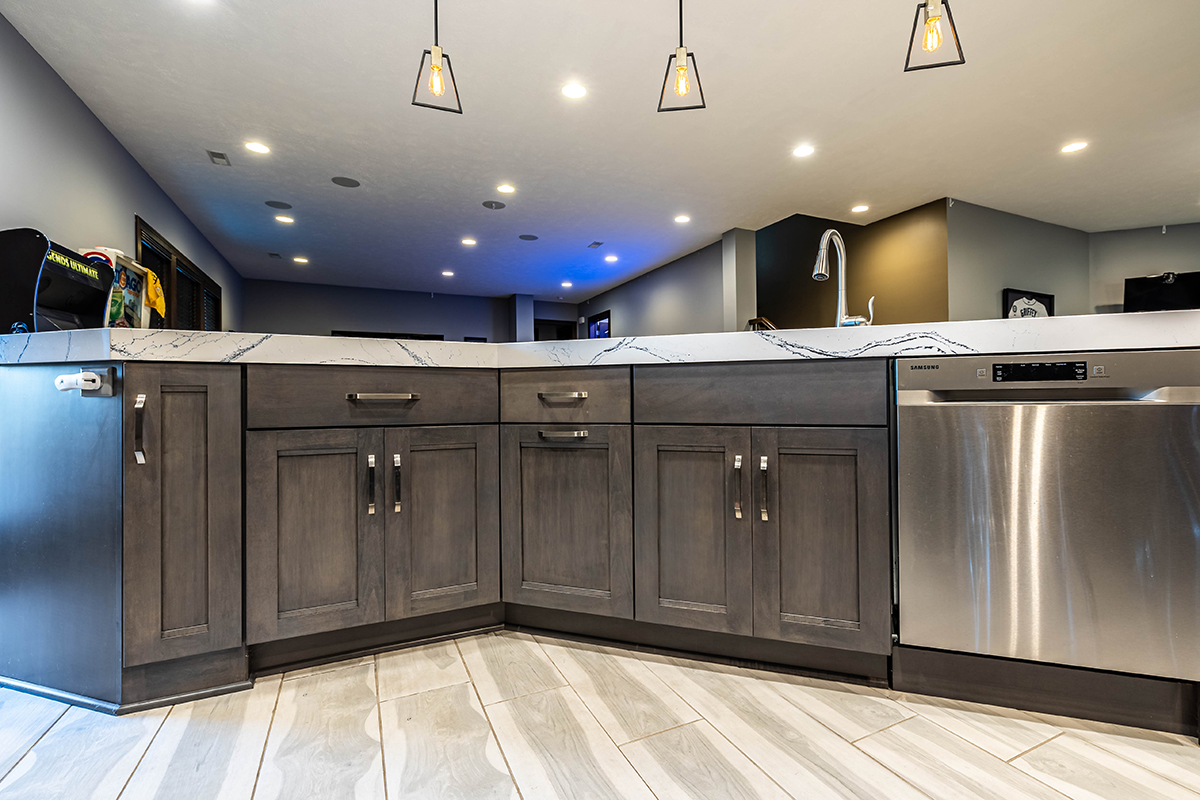 Another view of the grey cabinets under the sink with the stainless steel hardware next to dishwasher.