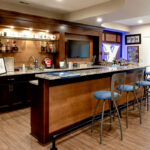 A sports bar in a basement family room that features dark brown cabinets.