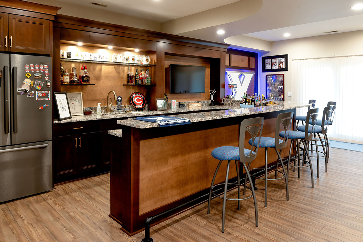 A sports bar in a basement family room that features dark brown cabinets.
