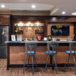 Wide view of the bar with the bar stools. We see the details of the dual toned wood features of the house.