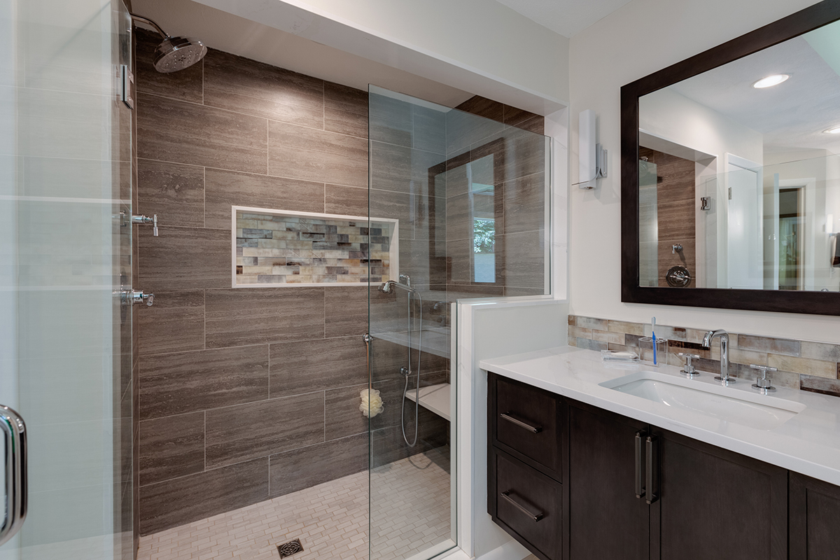 A big glass shower with multiple shower heads. The shelving is a built in box into the wall.
