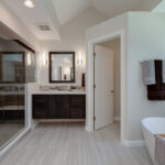 An opposing view of the bathroom that shows another sink that mirrors the first sink. The large shower is across from the soaking tub.