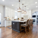 White cabinets along the wall, a dark brown island, and cherry wood floor.