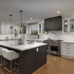 A full view of the large island. The range and range hood are prominent in this photo. The range is a brushed brown color.