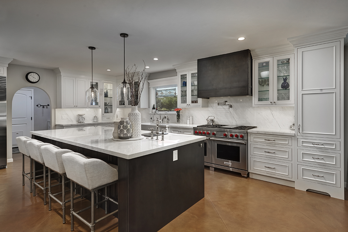 A full view of the large island. The range and range hood are prominent in this photo. The range is a brushed brown color.