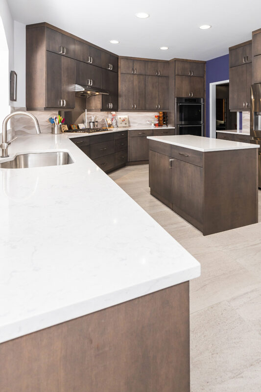 brown kitchen cabinets with white counter tops in large diagonal kitchen