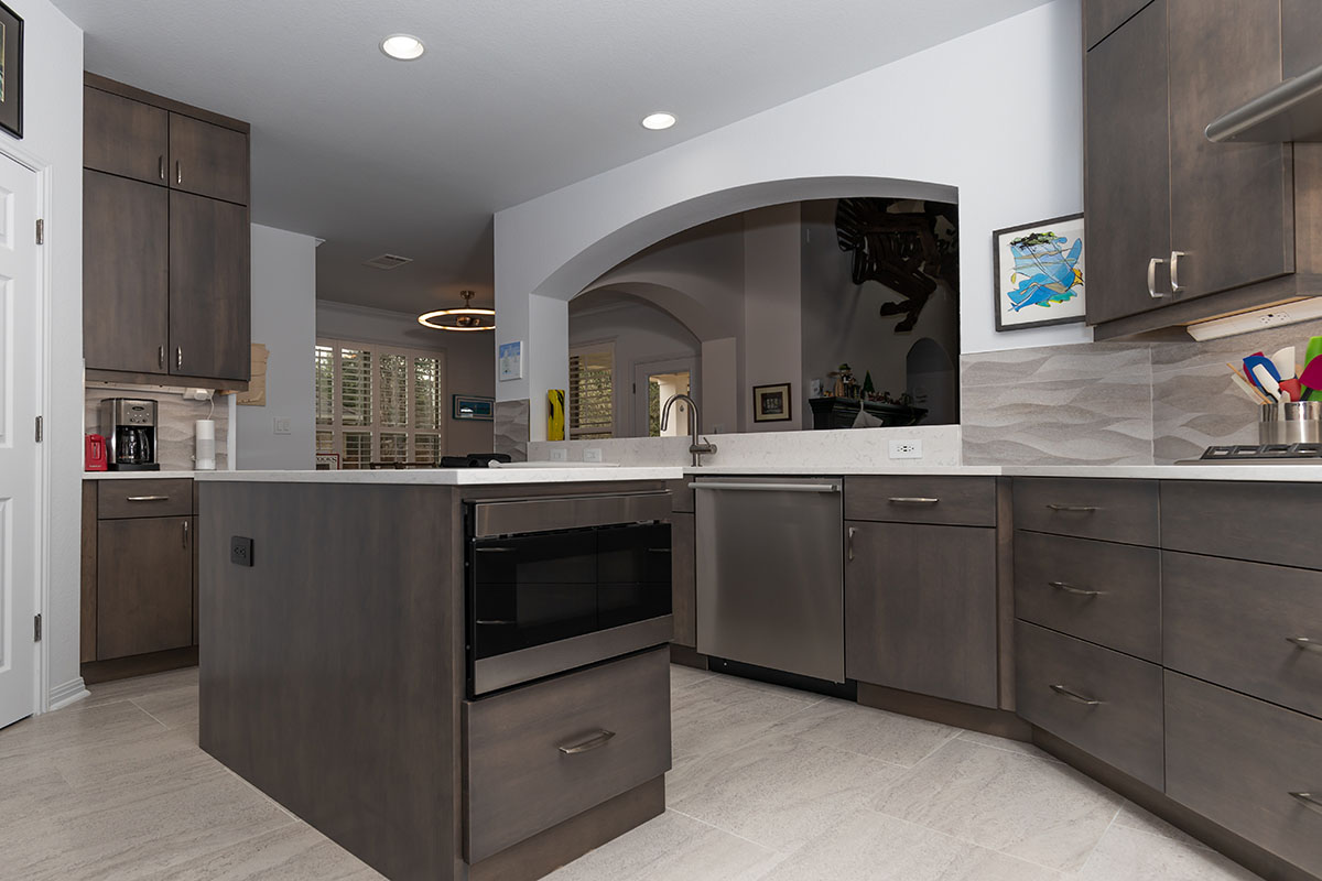 large cutout in wall opening up to brown kitchen cabinetry and appliances