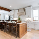 Hickory island and large focal beam are the centerpieces to this kitchen. The exterior walls of the kitchen have white cabinets.