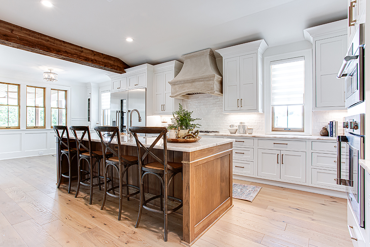 Hickory island and large focal beam are the centerpieces to this kitchen. The exterior walls of the kitchen have white cabinets.