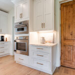 Double ovens are built-in to the walls. We see the gold hardware more prominently.