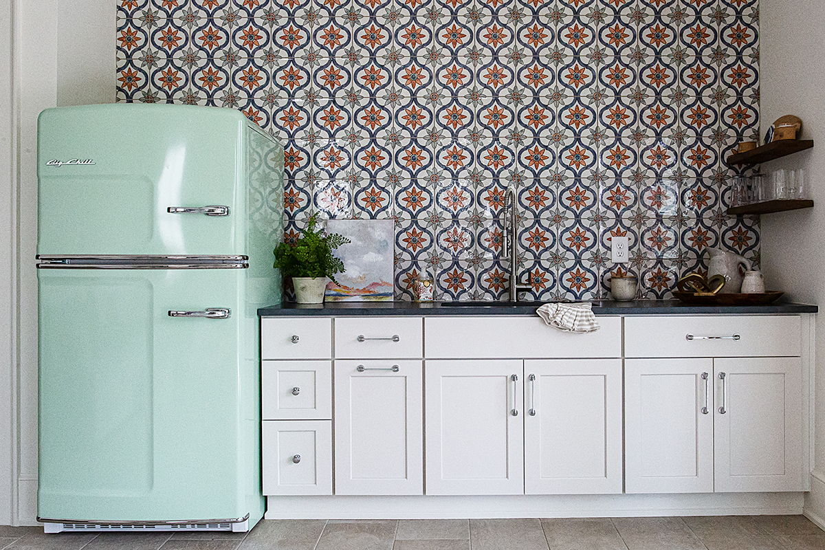 White cabinet, blue-green with greek inspired tile in the background.