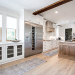 Long view of the kitchen with the big fridge, mesh-faced cabinets, and hickory island.
