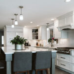 White kitchen cabinets with silver handles outline the exterior walls of the kitchen. The island is large in the center of the kitchen.