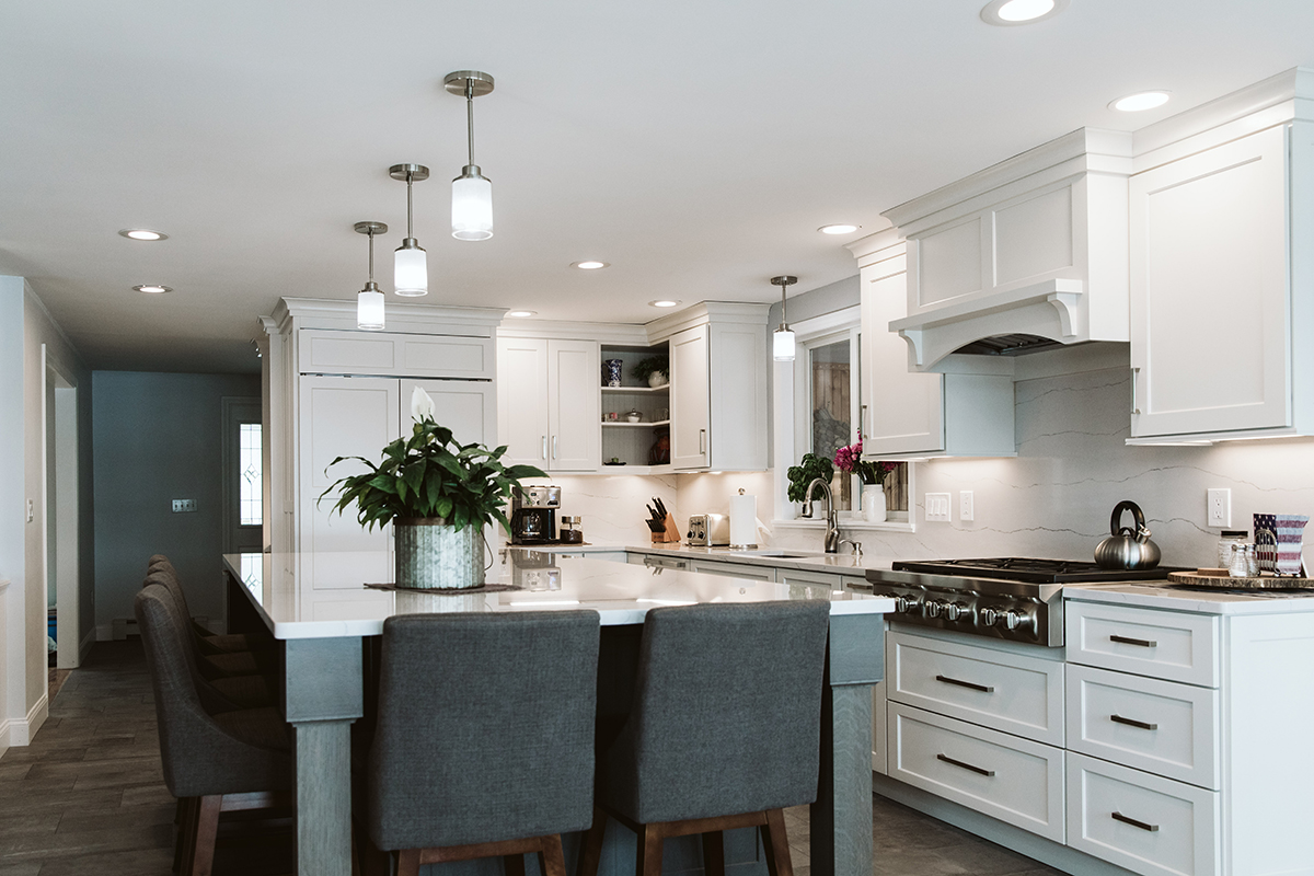 White kitchen cabinets with silver handles outline the exterior walls of the kitchen. The island is large in the center of the kitchen.