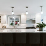 Another view of the island with the dark base in contrast to the white cabinets with white backsplash.