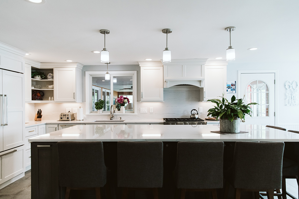 Another view of the island with the dark base in contrast to the white cabinets with white backsplash.