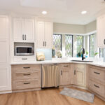 A view of the exterior wall of the kitchen with floor-to-ceiling pantry, under the counter dishwasher, corner sink, and beautiful windows.