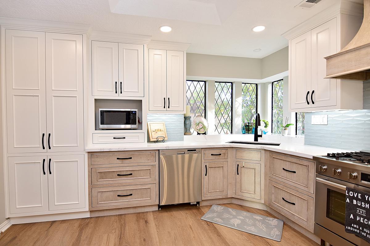 A view of the exterior wall of the kitchen with floor-to-ceiling pantry, under the counter dishwasher, corner sink, and beautiful windows.