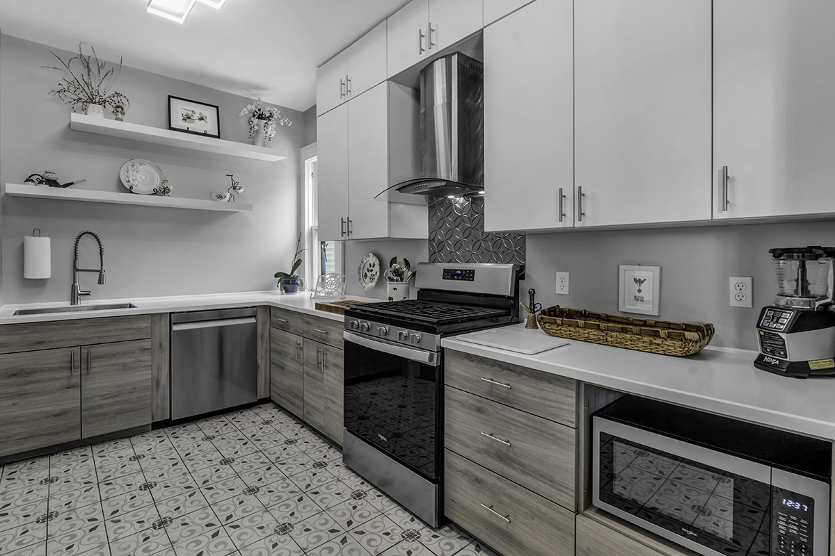 Small City Kitchen. Brushed grey lower cabinets, and white upper cabinets. open shelving that is white. Stainless steel appliances around the mostly grey kitchen.