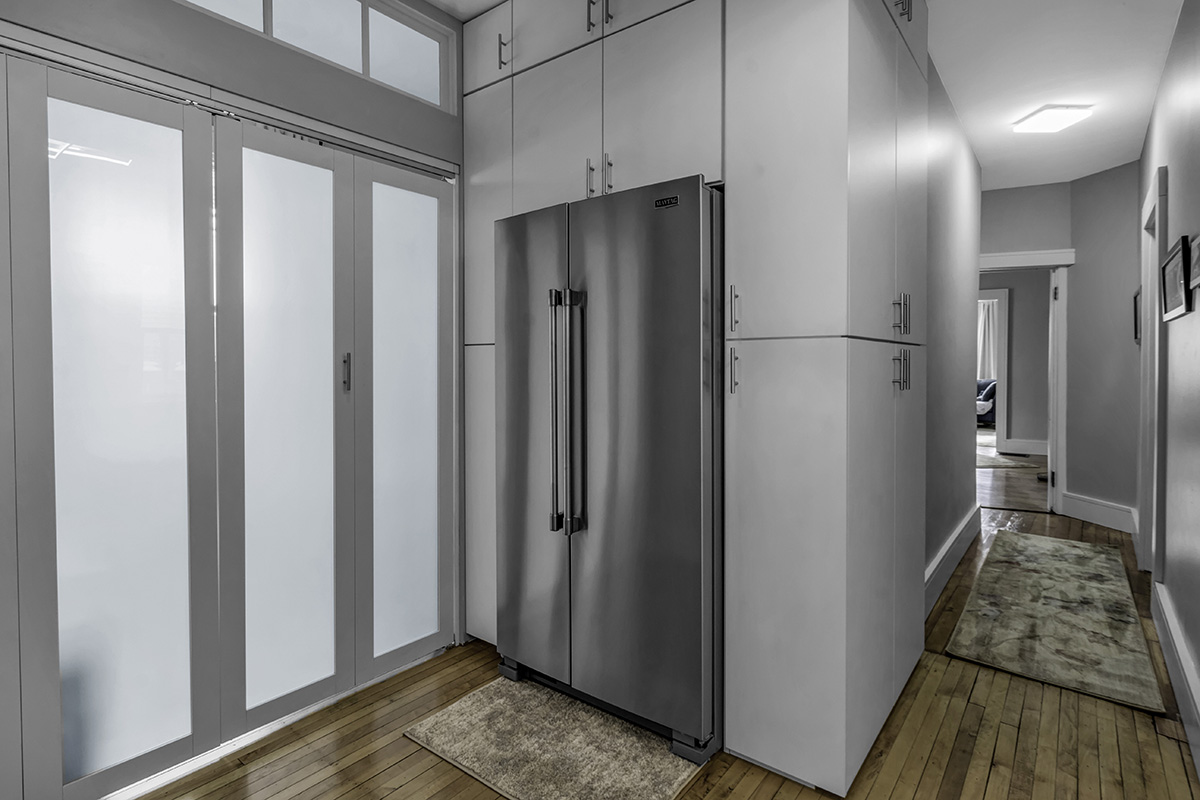 frosted glass doors near gray kitchen cabinetry and stainless steel fridge.