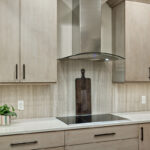 light natural cabinets that have a similar natural-colored stone backdrop. This picture shows a built in stove with a lean hood.