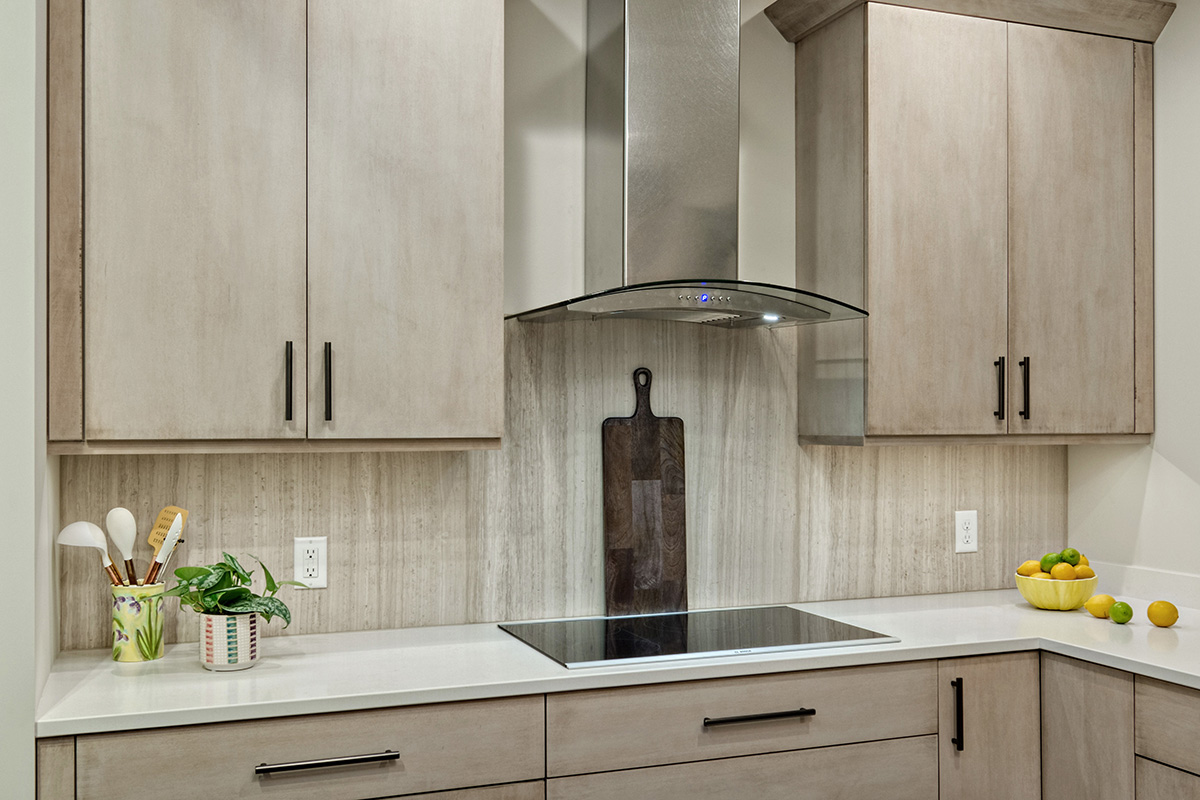 light natural cabinets that have a similar natural-colored stone backdrop. This picture shows a built in stove with a lean hood.