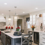 this kitchen is majority white, but the island is a dark grey color. The appliances are stainless steel, and the kitchen hard is silver. The kitchen has silver light fixtures.
