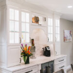 Coffee bar with glass faced cabinets that are lit.