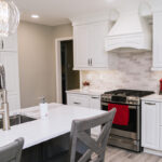We see that the sink is built into the island in this kitchen. The gas range is off to the right of the photo with a custom white range hood.