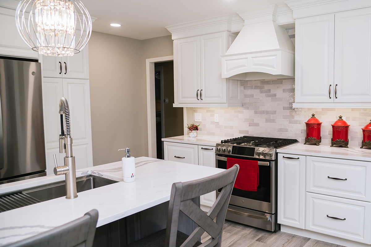 We see that the sink is built into the island in this kitchen. The gas range is off to the right of the photo with a custom white range hood.