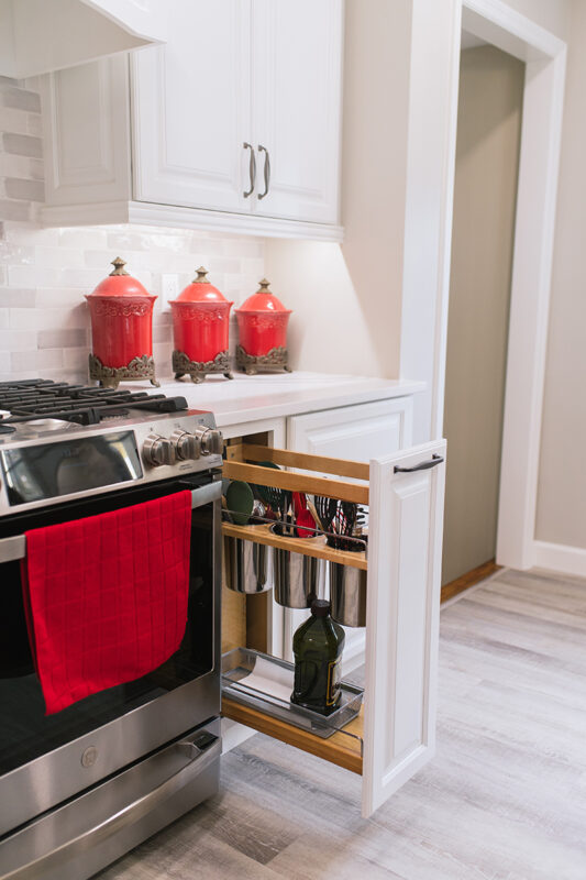 Beside the stove there is a pull-out drawer that holds cooking tools and cooking oil.