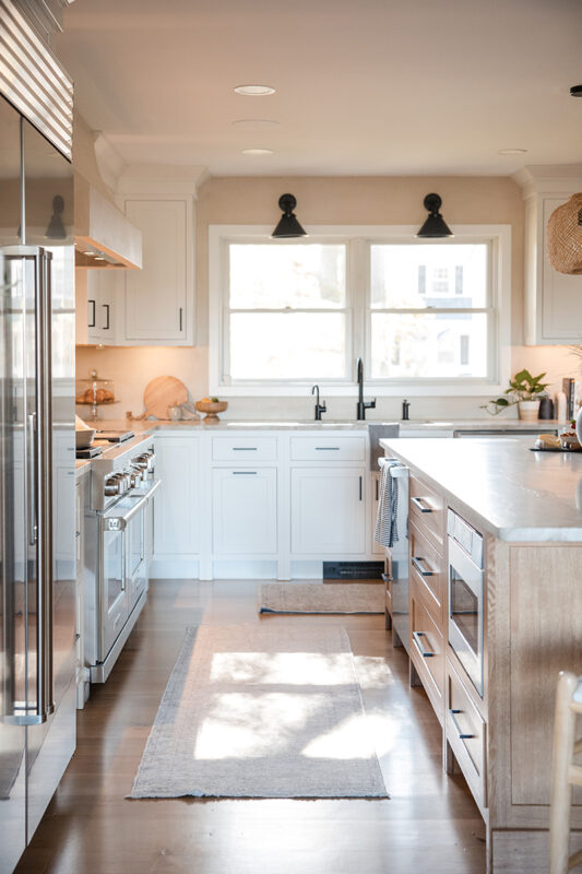 white kitchen cabinetry with stainless steel appliances. The island is filled with brown wooden cabinets.